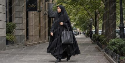 زن جوان با پوشش چادر در حال قدم زدن در خیابان